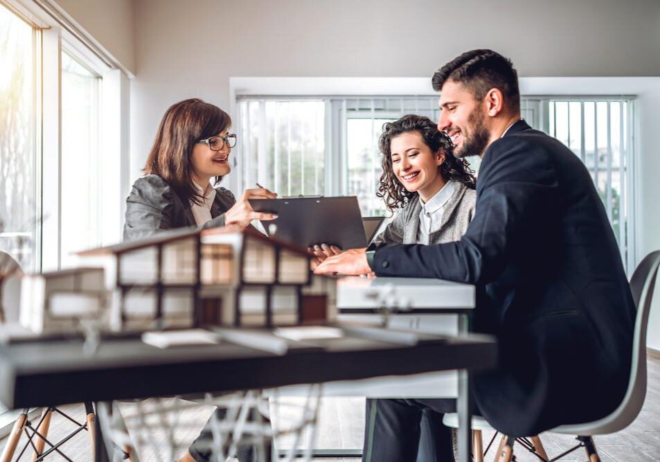 Side view image of young happy family sitting in consulting office, making property purchase. Mature female realtor helping business couple do financial investment. Installment payment, mortgage, loan for estate concept